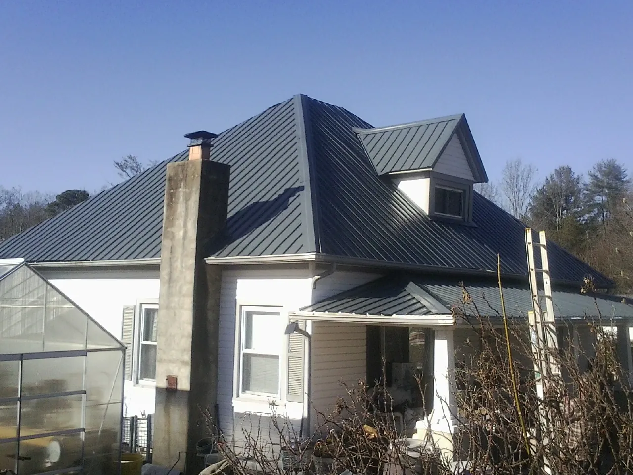 Dark blue standing seam metal roof on a white farmhouse with dormer — Slate & Tile Roof Repair by Roofing Brothers in Fork