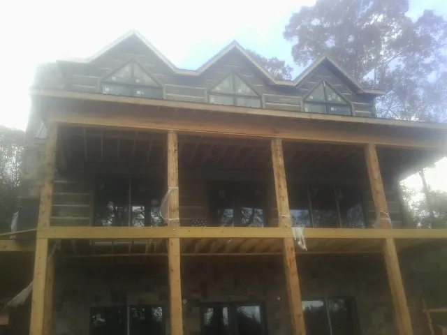 Dormers and porch framing on a large log home under construction — Roof Coating work by our crew in Fork
