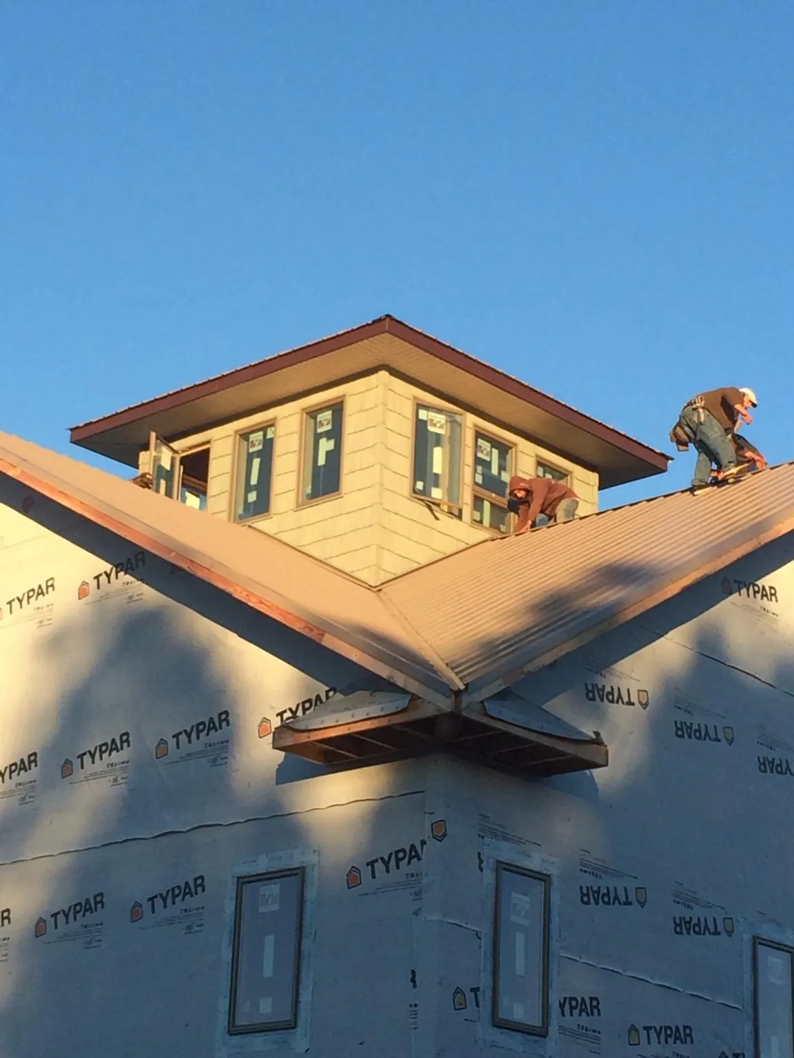 Roofers working around a rooftop cupola on a new metal roof at sunset — Roof Waterproofing in Fork by Roofing Brothers
